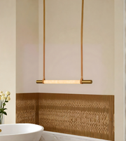 Modern pendant light fixture in a bathroom setting with a decorative wall panel.