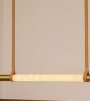 Modern pendant light with gold frame and white bulb on a beige background