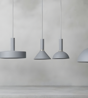 Three gray pendant lights hanging against a plain wall.
