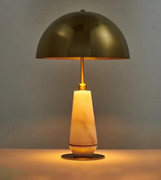 Table lamp with a gold metallic shade and beige ceramic base on a neutral background