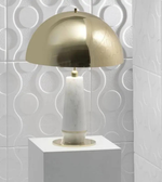 Gold and white table lamp on a white pedestal against a light gray tiled wall.