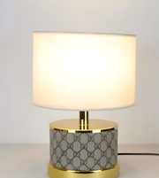 Table lamp with white shade and patterned base on a neutral background