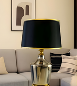 Decorative table lamp with black shade and gold trim in a living room setting.