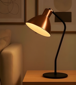 Copper desk lamp on a wooden surface with a warm glow