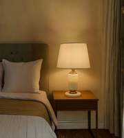 Bedroom scene with a bed and nightstand featuring a lamp.