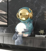 Decorative lamp shaped like an astronaut holding a light bulb on a shelf.