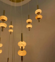 Modern pendant lights with glass shades and brass fixtures against a neutral background