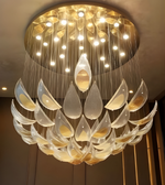 Luxurious chandelier with glass leaves and gold accents in a dimly lit room.