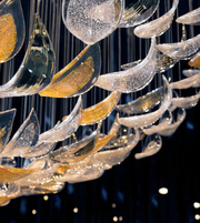 Close-up of a luxurious chandelier with gold and clear glass elements against a dark background.