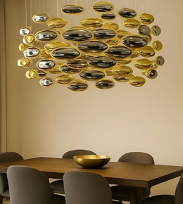 Modern chandelier with gold and silver design above a dining table and chairs.