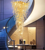 Luxurious chandelier hanging in a modern interior setting with a staircase and decorative elements.