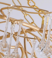 Gold chandelier with clear glass droplets against a light background