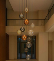 Modern chandelier with glass globe lights hanging in a room with a staircase.