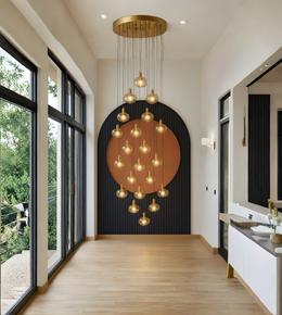 Modern interior with a large chandelier hanging in a room with large windows and a black wall.