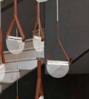 Close-up of a modern pendant light fixture with brown leather straps against a dark background.