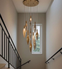 Modern chandelier hanging in a stairwell with a window in the background