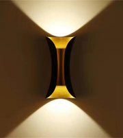 Gold wall sconce casting light on a wall