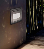 Light fixture on a wall with bamboo plants in the background