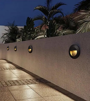 Outdoor wall lights on a concrete wall with palm trees in the background