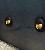 Two round outdoor lights embedded in a concrete wall.
