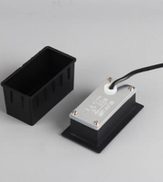 Black rectangular box with a metallic component on a gray background