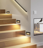 Wooden staircase with built-in lighting and a fireplace in the background.