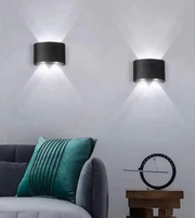 Modern wall lights on a white wall with a gray sofa and decorative pillow in the foreground.