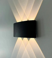 Modern wall-mounted light fixture casting geometric shadows on a gray wall.