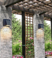 Pergola with stone columns and wall-mounted lights in a garden setting