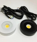 Two LED lights, one white and one black, with wiring on a white background.