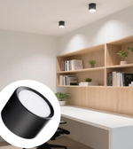 Modern office space with wooden bookshelf and desk, featuring a black ceiling light fixture.