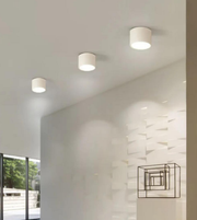 Three ceiling lights on a white ceiling with a modern wall design in the background.
