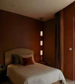 Bedroom with a bed and lamp against a brown wall