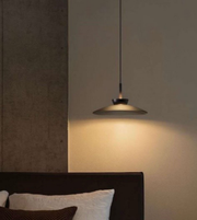 Modern pendant light hanging above a bed in a bedroom setting