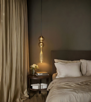 Modern bedroom with a bed, side table, and hanging lamp.