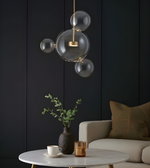 Modern interior with a bubble pendant light, table, and chair against a dark paneled wall.