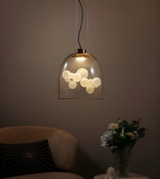 Pendant light fixture with glass shade in a dimly lit room.