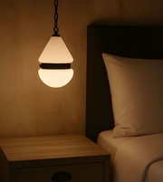 Light bulb hanging above a bed in a dimly lit room