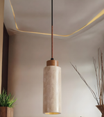 Pendant light fixture with a cylindrical shade in a room setting.