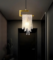 Modern chandelier hanging in a dimly lit room with a dark door and cactus plant.