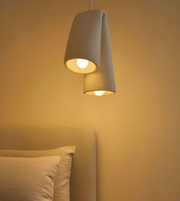 Modern pendant light fixture on a neutral wall with pillows in the foreground