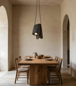 Dining area with wooden table and chairs under a pendant light in a room with arched doorways.
