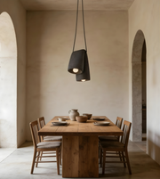 Dining area with wooden table and chairs under a pendant light in a room with arched doorways.