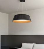 Black pendant light hanging above a bed in a bedroom setting
