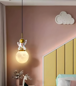 Decorative pendant light in a room with pink wall and yellow headboard