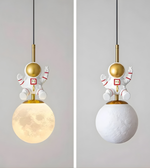 Two pendant lights with astronaut designs on a plain background
