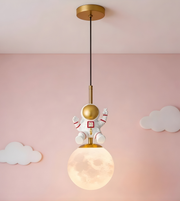 Children's pendant light with astronaut design against a pink wall