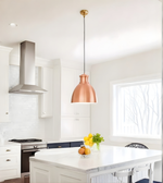 Modern kitchen with a copper pendant light, white island, and stainless steel range hood.