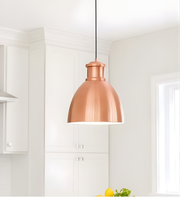Copper pendant light hanging in a kitchen with white cabinets and a window.