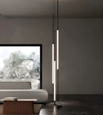 Modern floor lamp in a minimalistic living room with a sofa and window view.